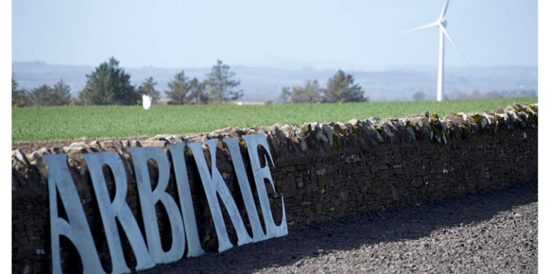 a sign reading Arbikie in front of a field