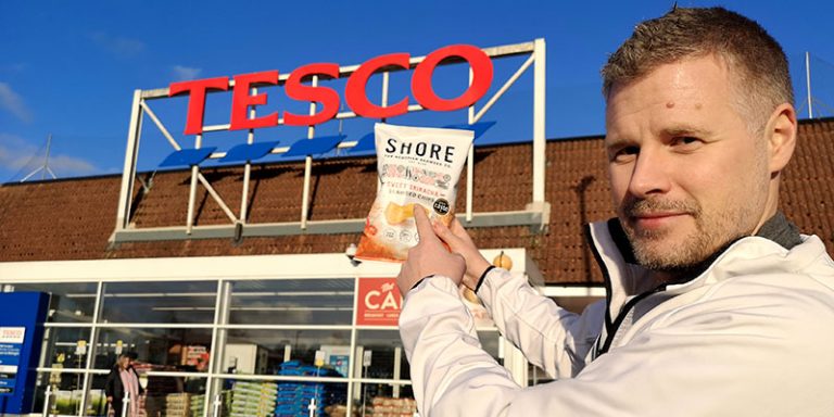 Man holding bag of crisps outside Tesco