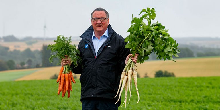 Man holding carrots and parsnips