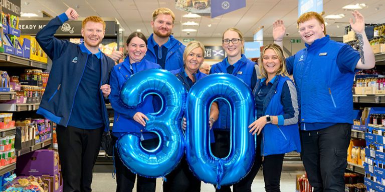 Smiling shopworkers with a number 30 balloon